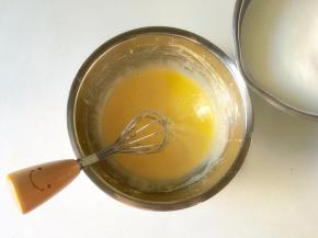 将煮沸的牛奶缓慢倒入蛋黄糊中并搅拌均匀