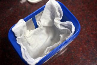 纱布用沸水煮一下，进行消毒。乳清过滤器用温水烫一下。将纱布放入乳清过滤器。