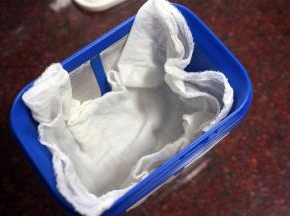 纱布用沸水煮一下，进行消毒。乳清过滤器用温水烫一下。将纱布放入乳清过滤器。