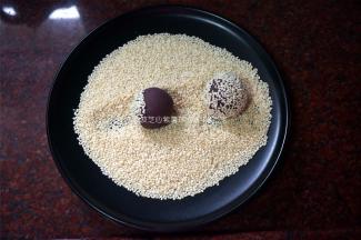 把紫薯球分别在芝麻上滚粘均匀，码放入盘内。
6、