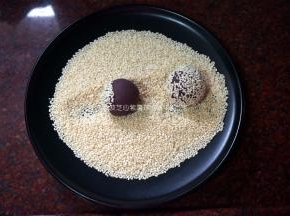 把紫薯球分别在芝麻上滚粘均匀，码放入盘内。
6、