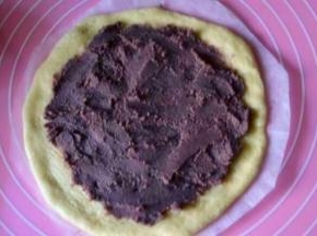 底下垫张油纸，把圆形面片放到上面，抹上一层豆沙，边上留一点距离不要抹，然后再放上第二片，再抹上豆沙，重复上面步骤把第三片盖到上面