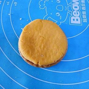 取一块饼干放在下面，取一块南瓜面团按扁放在饼干上