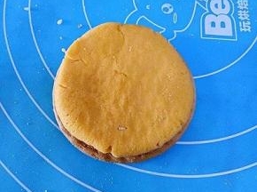 取一块饼干放在下面，取一块南瓜面团按扁放在饼干上