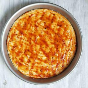 披萨饼上放一大小披萨酱，用勺子背面涂抹均匀