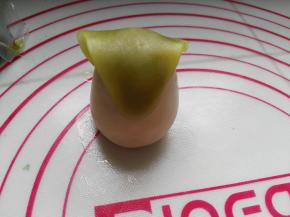 将大的水滴状绿茶小面团盖住牛奶桃山皮面团的小头，宽的一头搭在后面（见图）