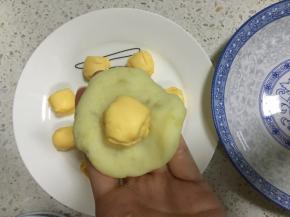 取适量搅拌好的土豆泥搓圆按扁，包入一个芝士球