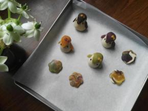 另外取适量台式桃山皮、咖啡桃山皮、绿茶桃山皮、紫芋味桃山皮、牛奶桃山皮，混合揉在一起，分成四份，搓圆、压扁做成四个岩石（见图），将小企鹅和岩石放入垫有油纸的学厨烤盘中