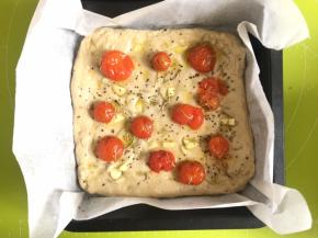 然后放上小番茄，撒适量黑胡椒碎，把大蒜片插入面团里，撒适量盐