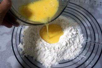 低筋粉，高筋粉，泡打粉混合过筛到揉面垫上，然后中间挖空，倒入全蛋液。