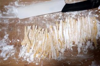 将大面片切成一段段的小面片，然后再切成细坯条，在皮条上撒上玉米淀粉防粘。