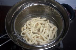 将一条坯条放入油锅试油温，若坯条迅速浮起涨大表示油温可以，开始放入坯条，炸坯条。