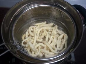 将一条坯条放入油锅试油温，若坯条迅速浮起涨大表示油温可以，开始放入坯条，炸坯条。