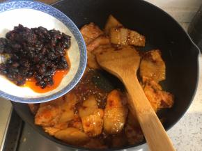 翻炒到五花肉微微卷起，加入豆豉、生抽、料酒、适量砂糖，翻炒均匀