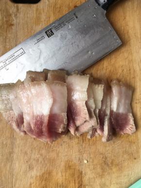 捞出五花肉过一遍凉水，然后切成薄片