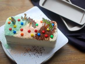 刨出适量的法芙娜巧克力碎，果味巧克力（绿色，橙色），将其铺到蛋糕表面上，最后用MM巧克力和小卡片装饰即可。