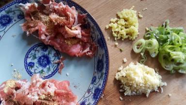 10．准备好葱姜蒜末，切好的羊肉上放入适量的胡椒粉和干姜粉磨。