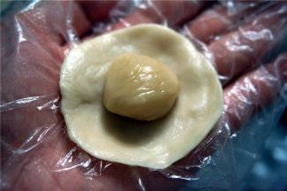 取一个水油皮弄成圆形，将油酥团放在中间，然后包起来，收口向下。