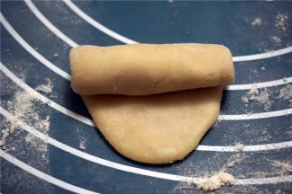 案板上洒少许面粉，用面杖将面团擀成椭圆形，由上往下卷起来。