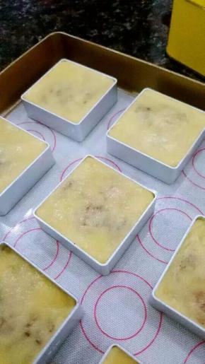 把凤梨酥模具摆在烤盘上，将包好的面团放到模具里面，用手把面团压平，使面团在模具里定型。