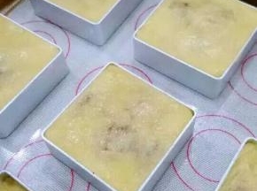 把凤梨酥模具摆在烤盘上，将包好的面团放到模具里面，用手把面团压平，使面团在模具里定型。