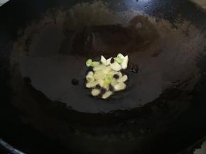 4、锅中放入花生油，放大蒜片，大葱段和豆豉煸香