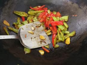 7、用锅铲背以画圈的方式按压青红椒，使其更加入味。