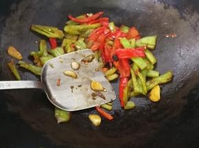 7、用锅铲背以画圈的方式按压青红椒，使其更加入味。