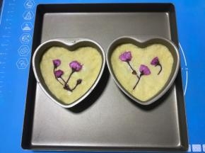 将冷藏好的面团分成两份，取一份用手压扁，包裹一份绿豆沙，用虎口慢慢向上收，直至收紧封口，滚圆后放入模具中，用手慢慢压平，再放上几朵樱花即可。