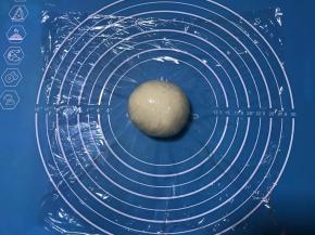 发酵好的面团排气后滚圆盖保鲜膜松弛15分钟。