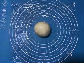 发酵好的面团排气后滚圆盖保鲜膜松弛15分钟。