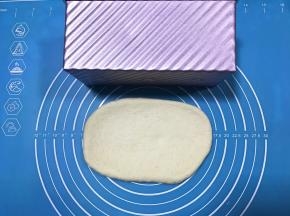 松弛完毕将面团擀成与土司盒差不多长的面片。