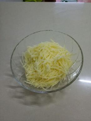 把土豆擦丝，放入碗中。