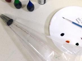 在裱花袋中装入裱花嘴，然后用描边笔蘸上色素刷在裱花袋内壁，每刷完一种色素都要清洗完再继续下一种色素的操作，以免混色。