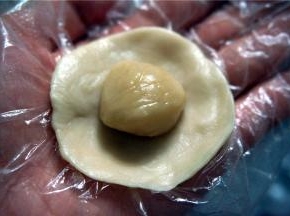 取一个水油皮压薄成圆形，将油酥团放在中间。