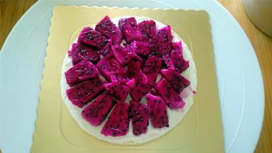 将蛋糕分成3等片，取一片，抹上一层奶油，放入一层火龙果肉，然后空隙填上淡奶油。