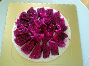 将蛋糕分成3等片，取一片，抹上一层奶油，放入一层火龙果肉，然后空隙填上淡奶油。