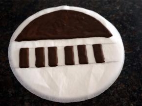 用一张圆形的8寸吸油纸转印钢琴键盘。融化了的巧克力，画出一个小半圆，画出长方形琴键，如图。然后放到冰箱冷冻层冻定型10分钟，取出。