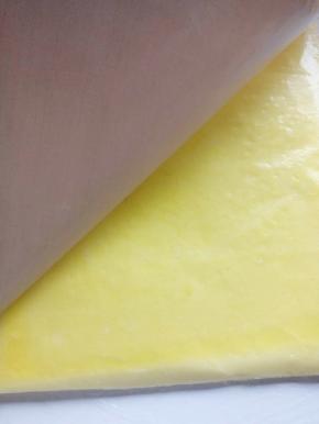 拎着油布拎出烤盘，晾个几分钟，取一个保鲜袋撕开盖蛋糕片上，把蛋糕片倒扣过来，撕开油布