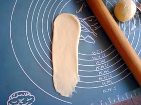 把面团擀成长条形，一边的短边擀簿