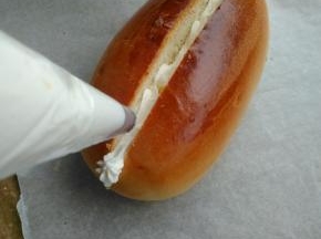 150克淡奶油加入15克细砂糖打至十分发，将打发好的淡奶油装进裱花袋内。在切开的面包内挤入奶油