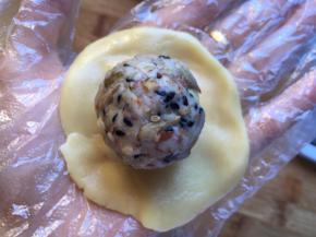 带上一次性手套，将饼皮压扁，伍仁馅放在中间