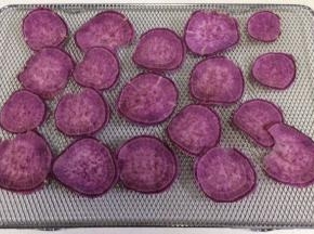 把紫薯片一一铺在烤网上。