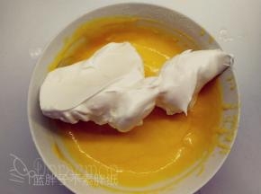 取1/3的蛋白霜加入到蛋黄糊中，用橡皮刮刀翻拌均匀。