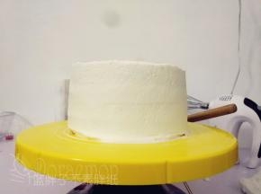 将蛋糕胚四周和顶部涂抹上一层淡奶油，盖住蛋糕胚。然后抹侧面。抹侧面时，抹刀垂直于蛋糕体，刀身贴紧侧面，转动裱花台，这样侧面就会慢慢变平。