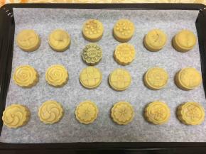 烤盘铺上烘焙纸，挑自己喜欢的花片，将模具在烤盘上按压一下，按出月饼成型。