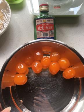 将现磕的咸蛋黄放入盆内，加少量白酒浸泡，将蛋清膜祛除