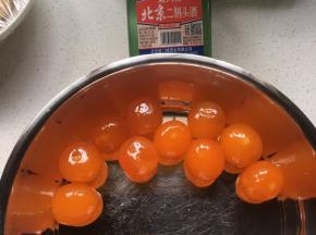 将现磕的咸蛋黄放入盆内，加少量白酒浸泡，将蛋清膜祛除