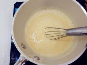 搅打均匀的蛋黄牛奶液倒回奶锅中，继续一边小火加热，一边用手动打蛋器搅打。