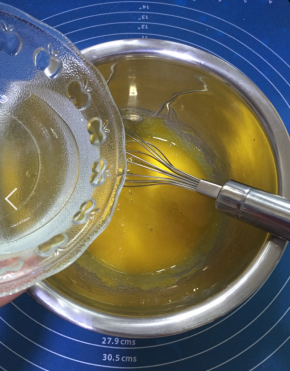 将热水玉米油的混合物缓缓加入蛋黄糊中，加入的同时用手动打蛋器搅拌
